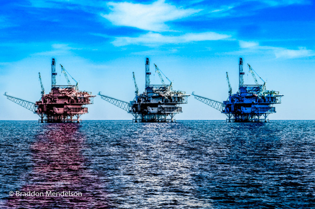 red, white, and blue oil derricks off the coast